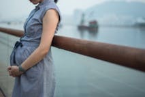 Photo: Kevin Liu/Getty Images 7 months pregnant women standing against a balustrade in a waterfront park along Victoria Harbour.