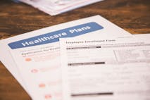Photo: fstop123/Getty Images Open enrollment healthcare benefit forms. - stock photo