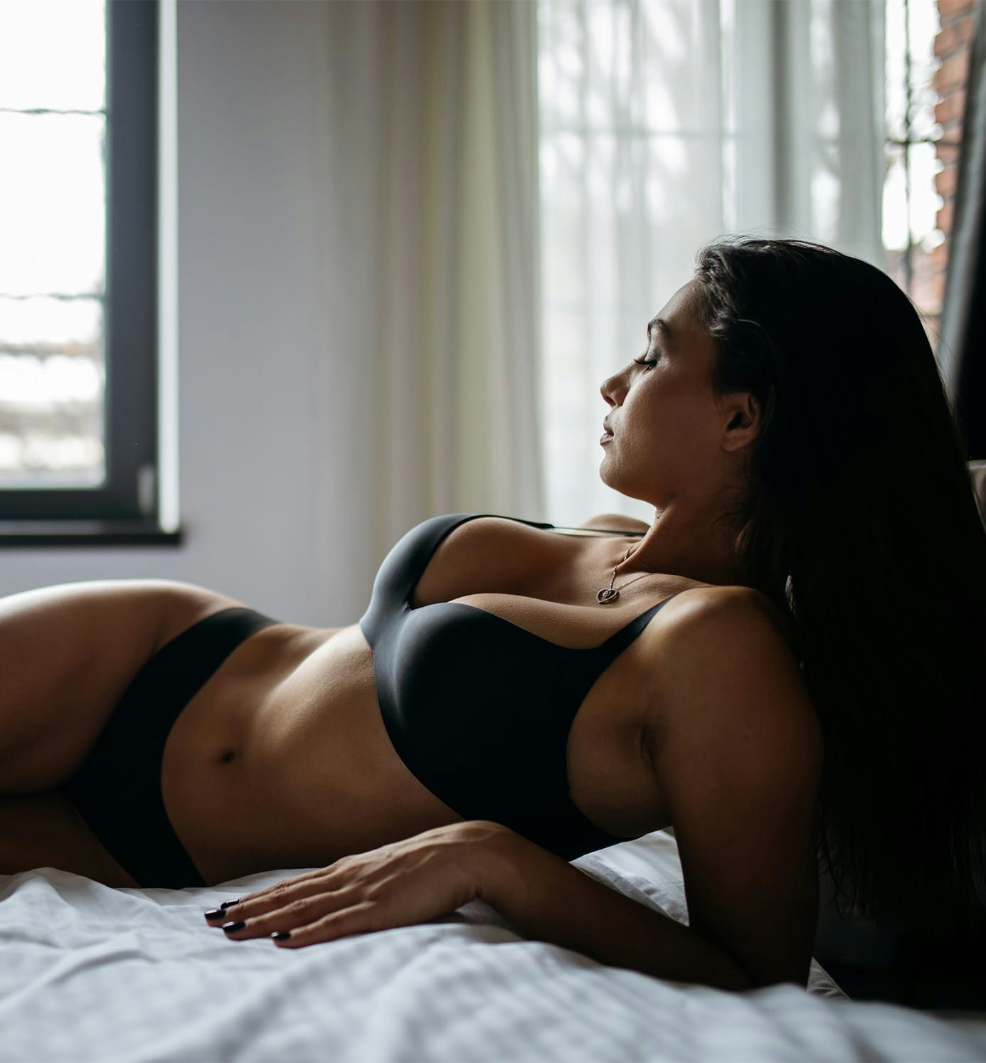 woman laying on bed in underwear looking down her body