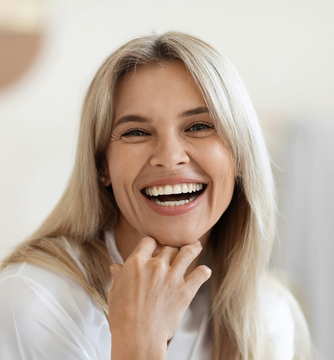 woman with blonde hair smiling with hand on her chin