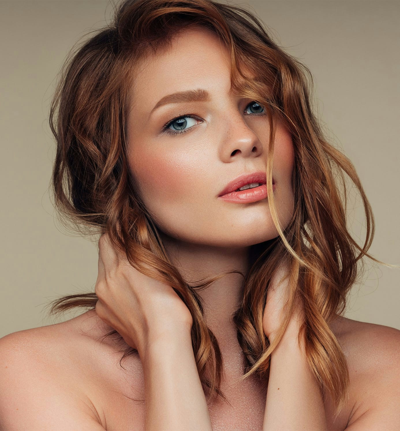 woman with wavy red hair with hands on her neck