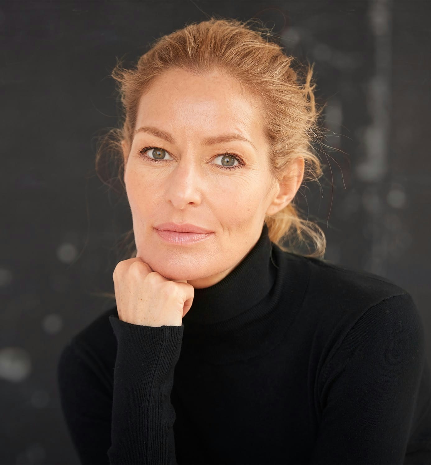woman with hair in a bun in black turtleneck