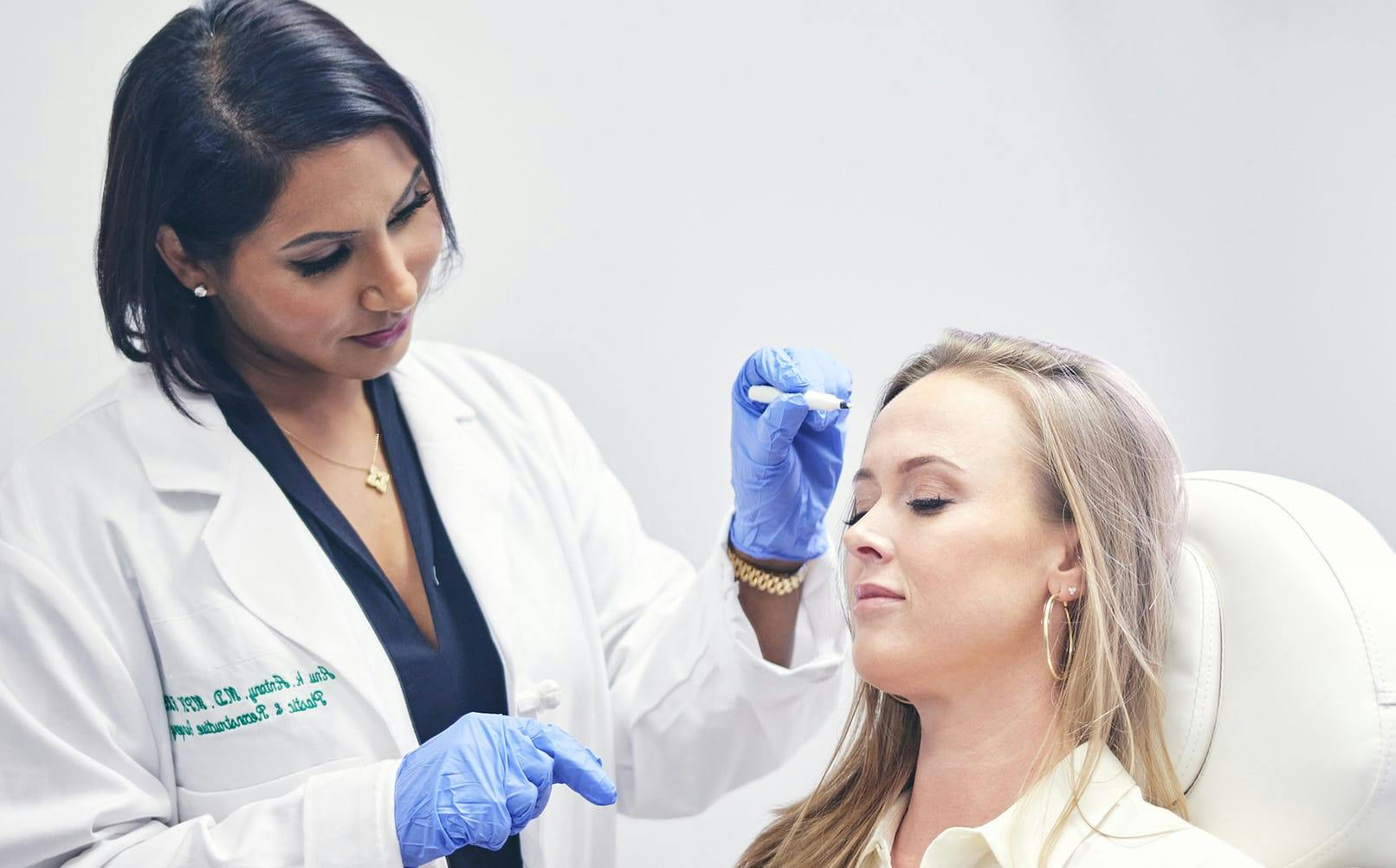 doctor holding marker near patient's forehead