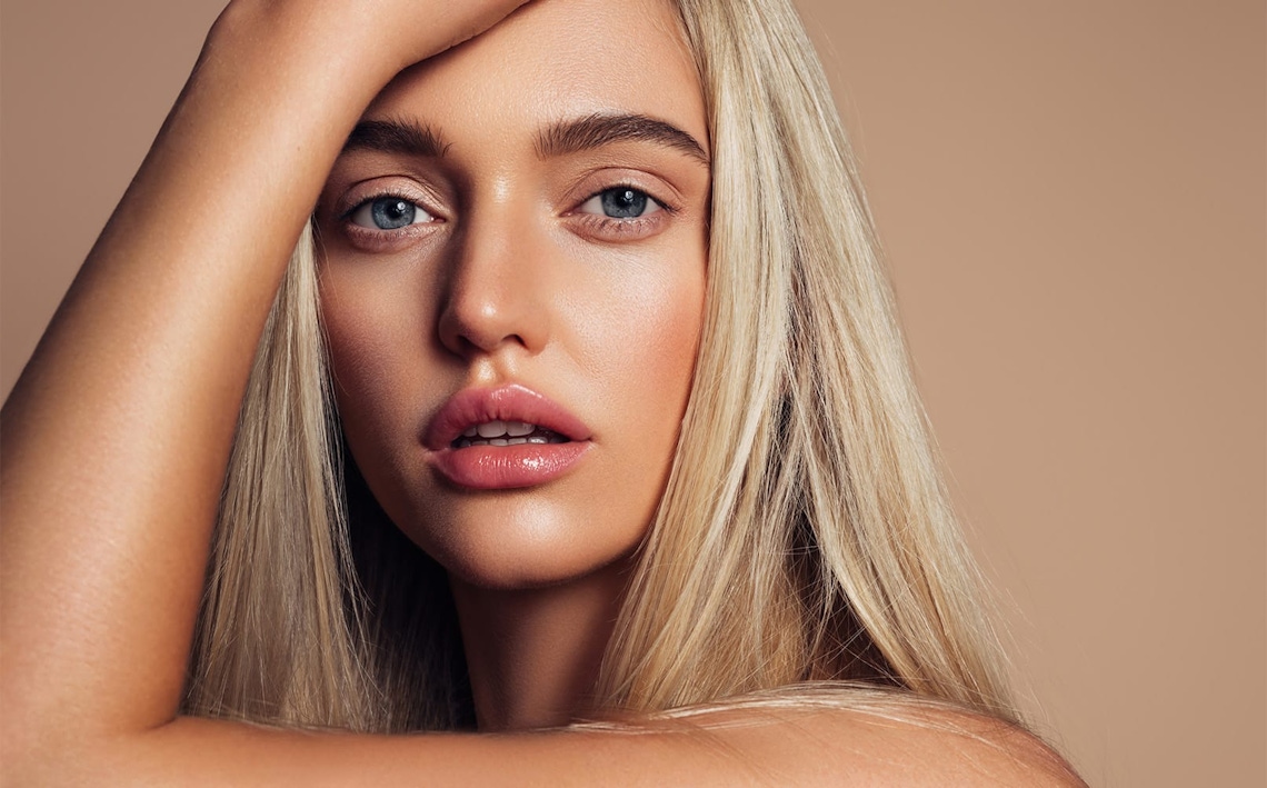 woman with blonde hair with hand over her face touching her head