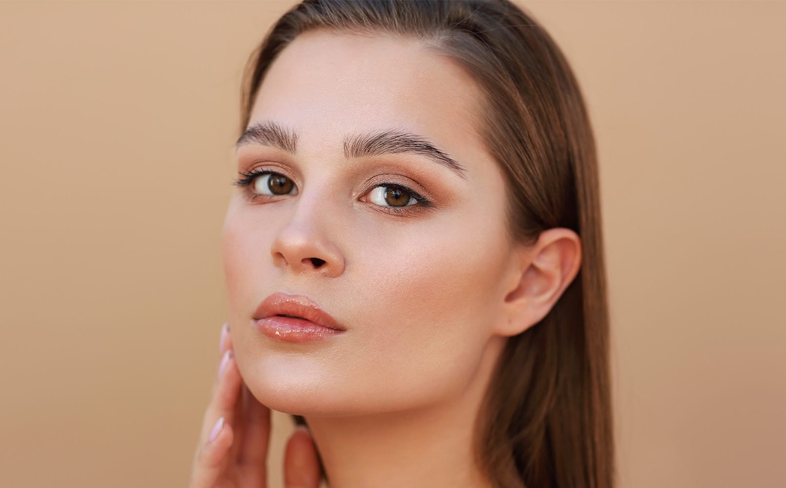 woman touching her jaw with straight brown hair