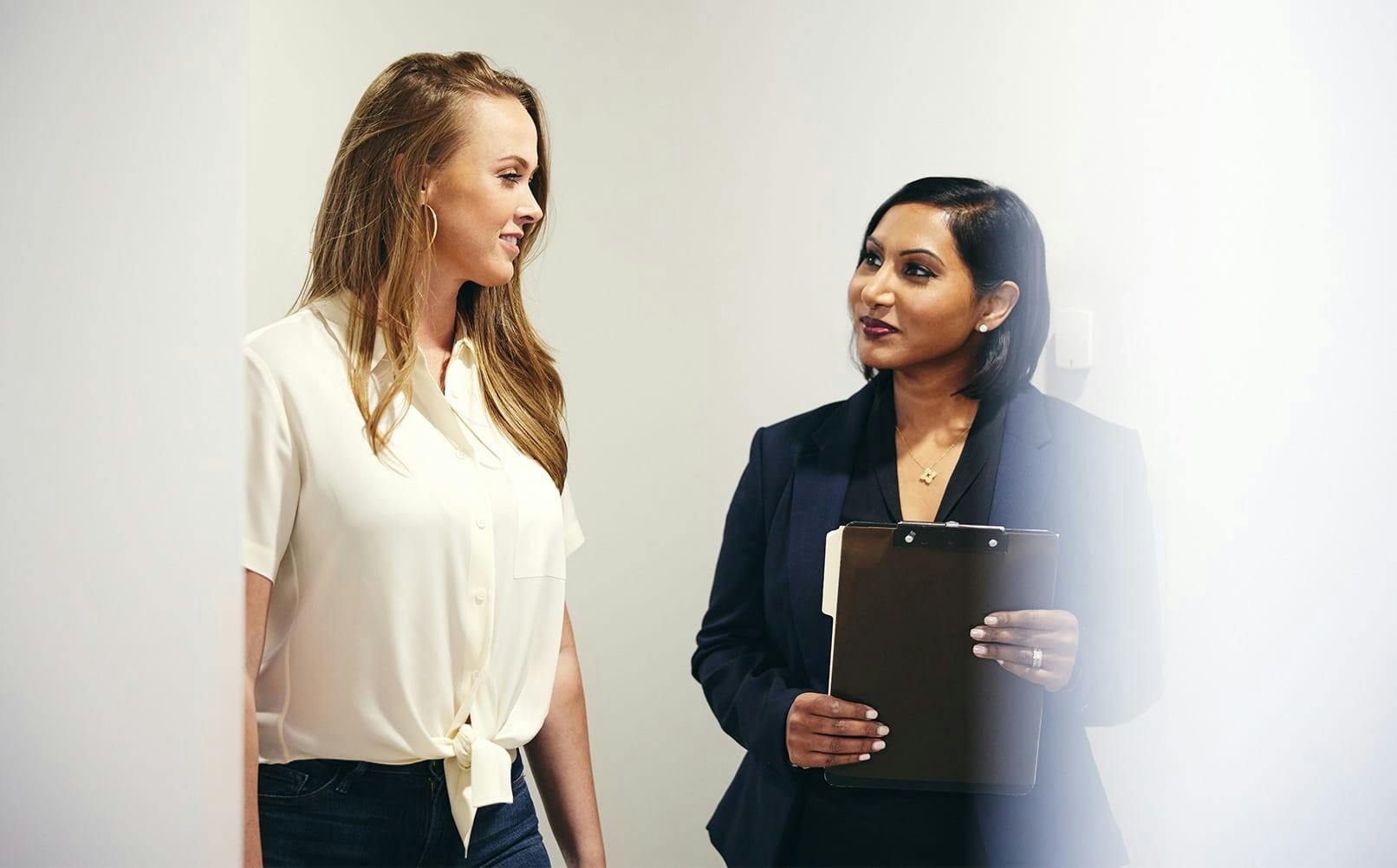 doctor holding clipboard with patient next to her