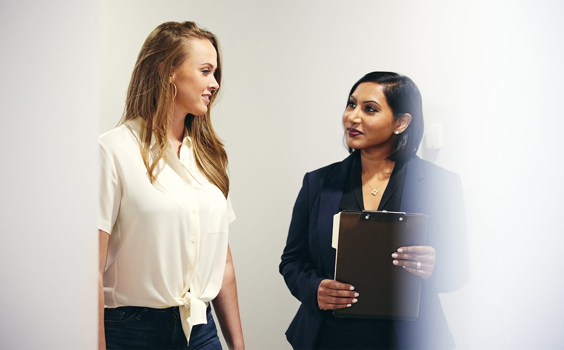 doctor holding clipboard with patient next to her