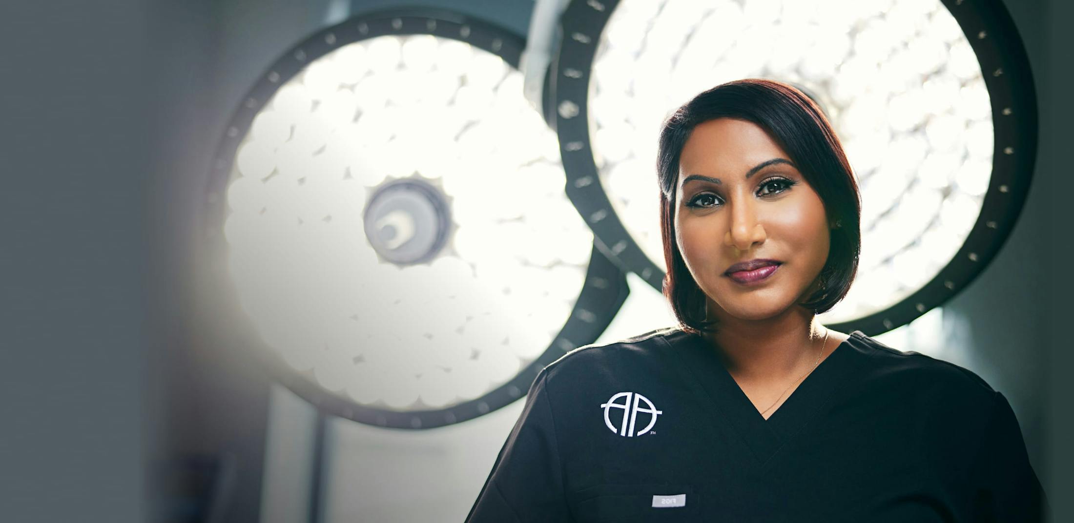 Dr. Anu Antony with operating room lights behind her