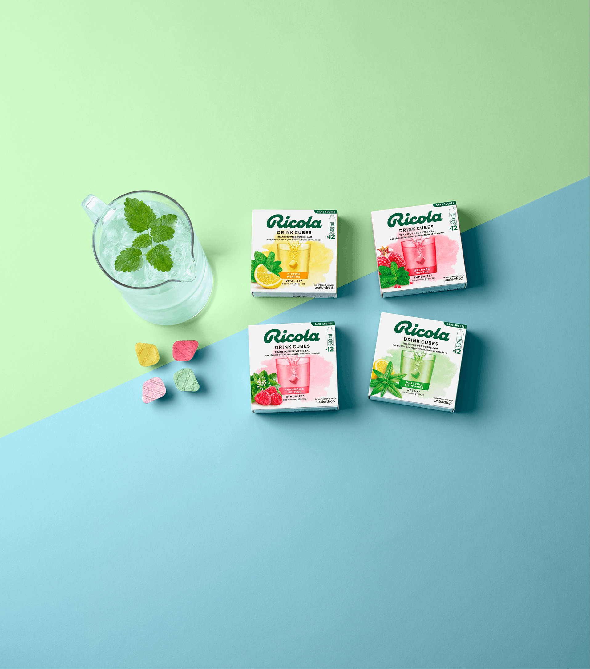 All Ricola Drink Cubes at a glance with a glass of mint drink against a soft blue-green background.