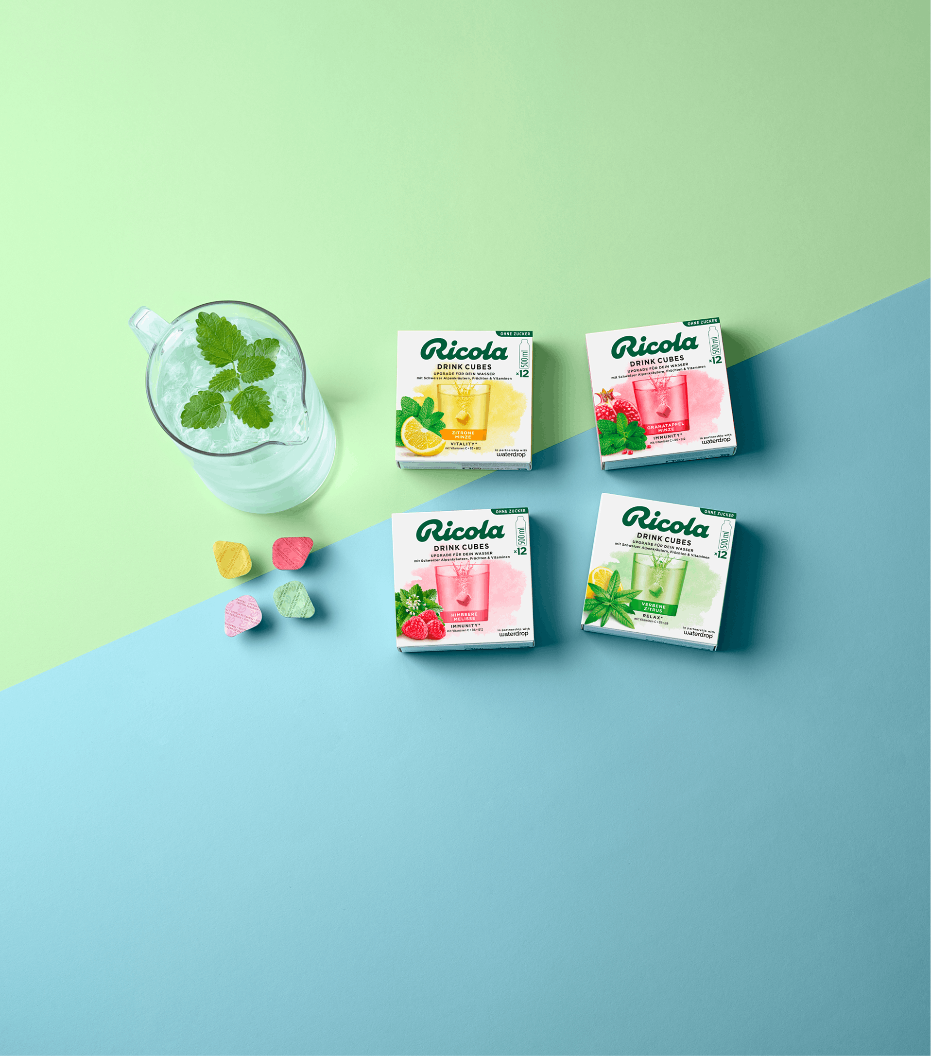 All Ricola Drink Cubes at a glance with a glass of mint drink against a soft blue-green background.