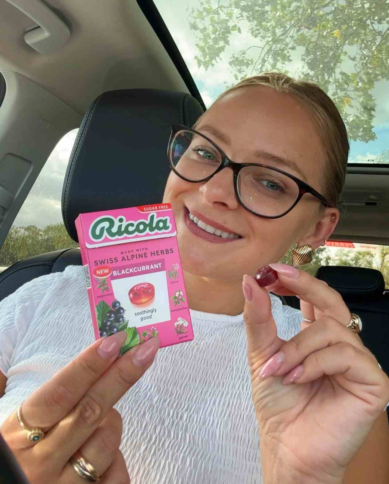 Woman holding Ricola Blackcurrant flavor Drops box