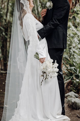 Bride and groom laughing in forest path