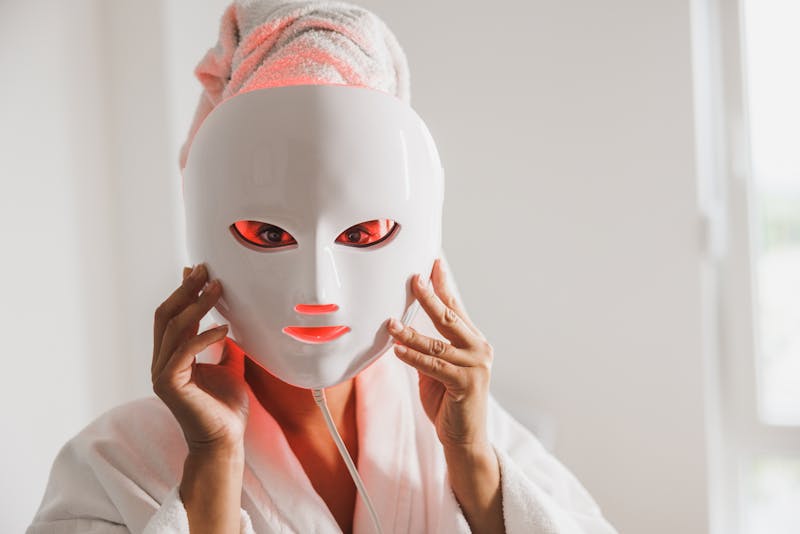 Woman wearing a red light therapy face mask at home