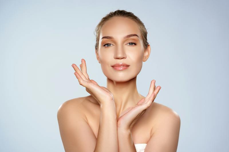 Woman posing with her hands framing her face and jawline.