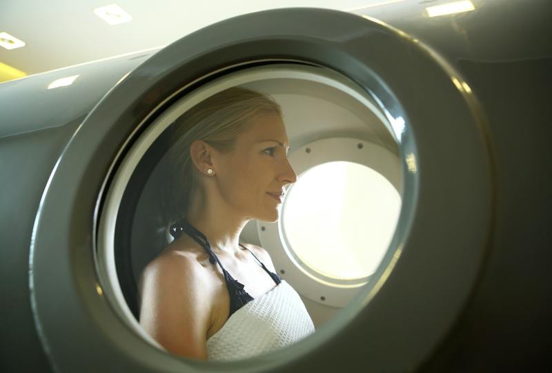 Woman receiving hyperbaric oxygen therapy inside a pressurized chamber.