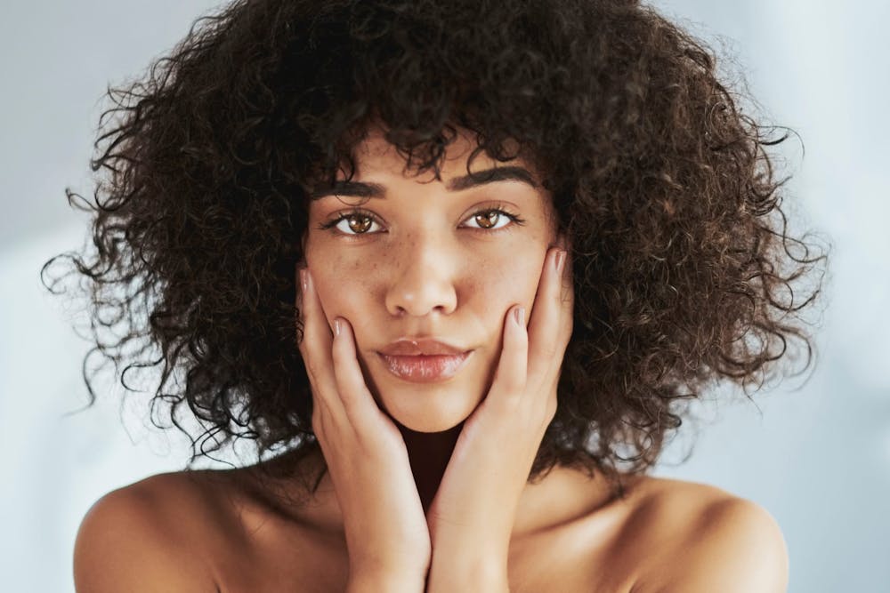curly-haired woman holding cheeks