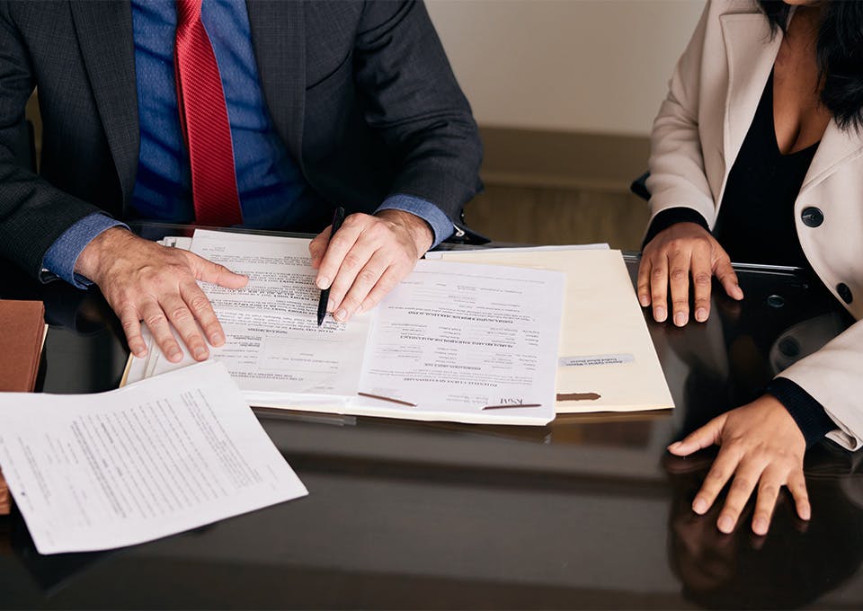 attorney pointing at paper in open folder on desk