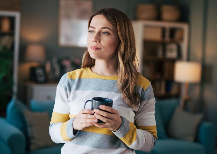 woman looking outside holding a mug
