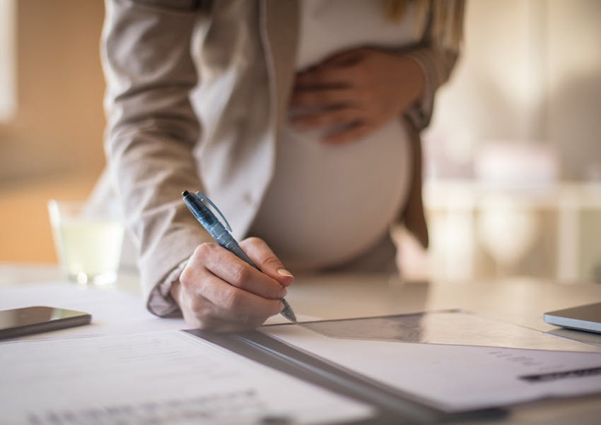 pregnant woman signing a document