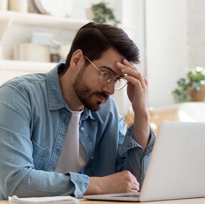 a worried man looking at laptop screen