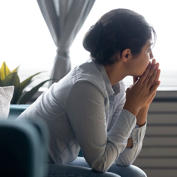 woman leaned forward with hands by mouth looking out window