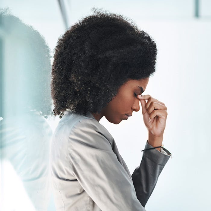 side shot of an afro'd woman touching nose with head down