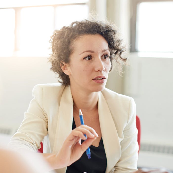woman with pen in hand talking