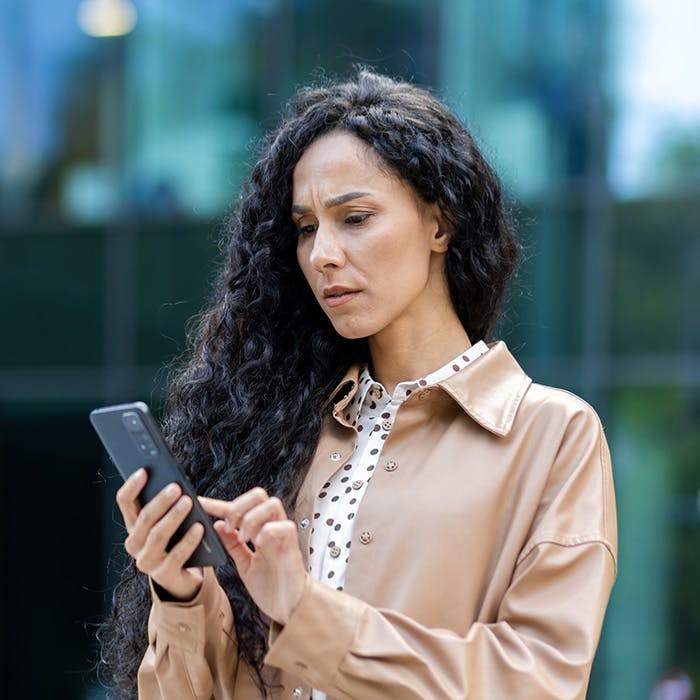 woman with eyebrows furrowed looking at cellphone