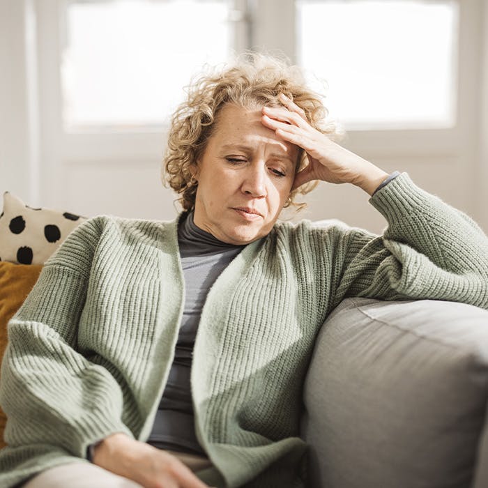 woman touching forehead looking down