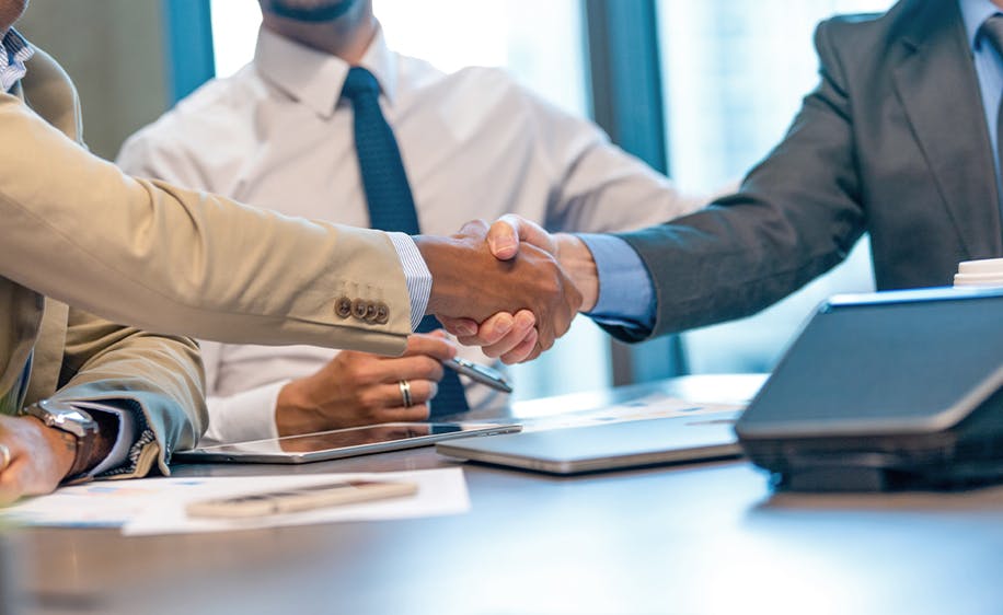 People shaking hands across a desk