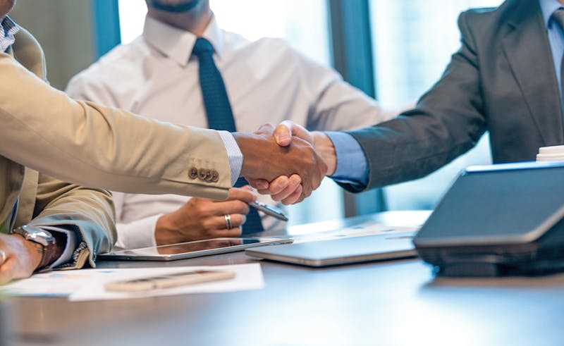 People shaking hands across a desk