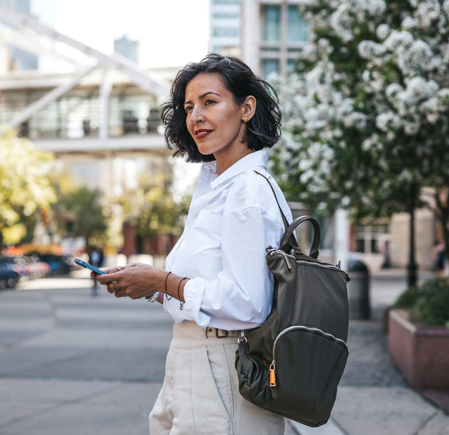 woman with a phone and backpack standing outside