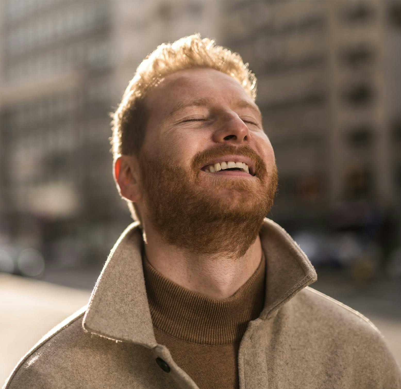 man looking up with closed eyes, smiling
