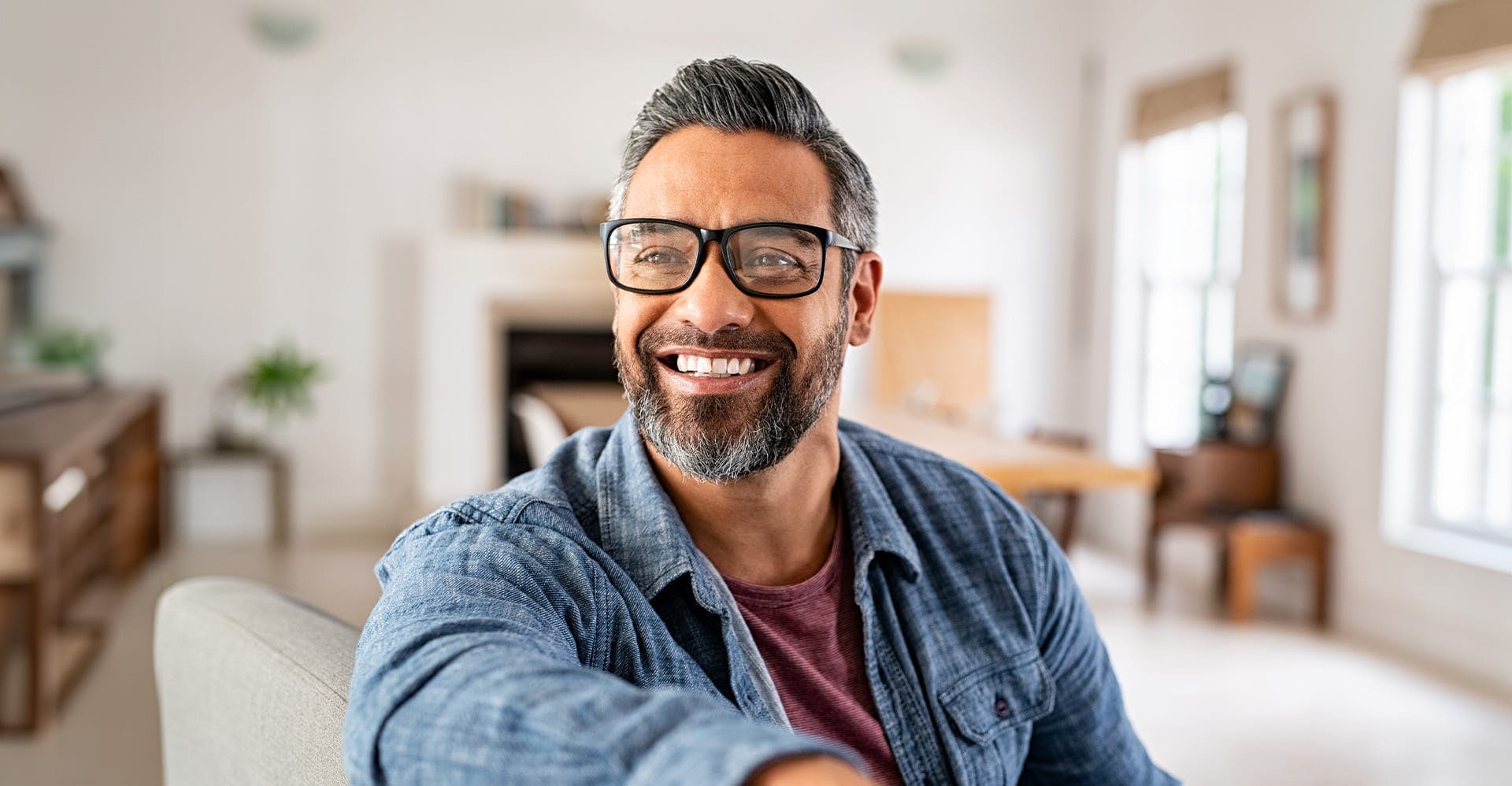 older man smiling, sitting on a couch