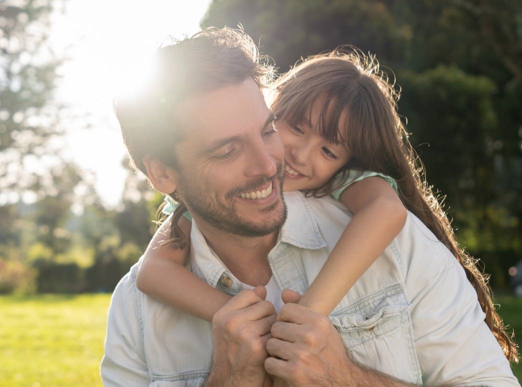 Man carrying his daughter on his back outside