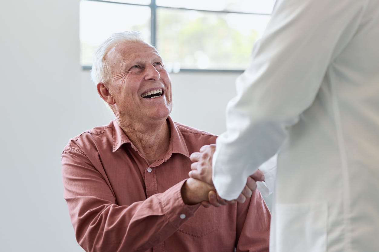 Older man sitting down shakes his doctors hand