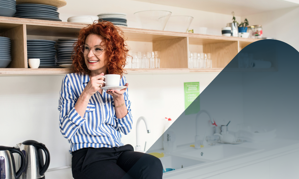 Smiling woman in kitchen with cup of tea