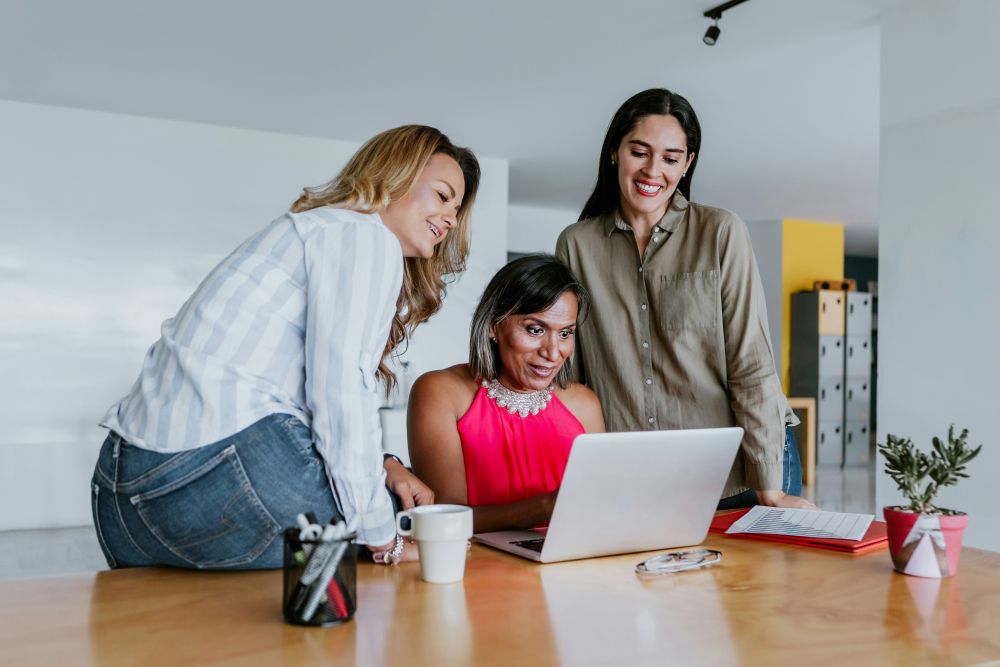 Three women looking at lap top screen together