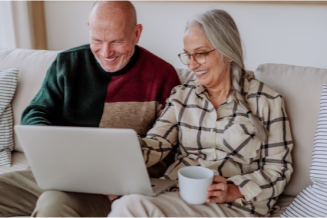 Two adults on lounge using a laptop computer