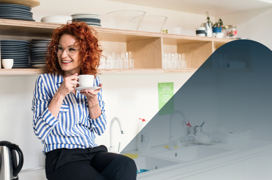 Smiling woman in kitchen with cup of tea