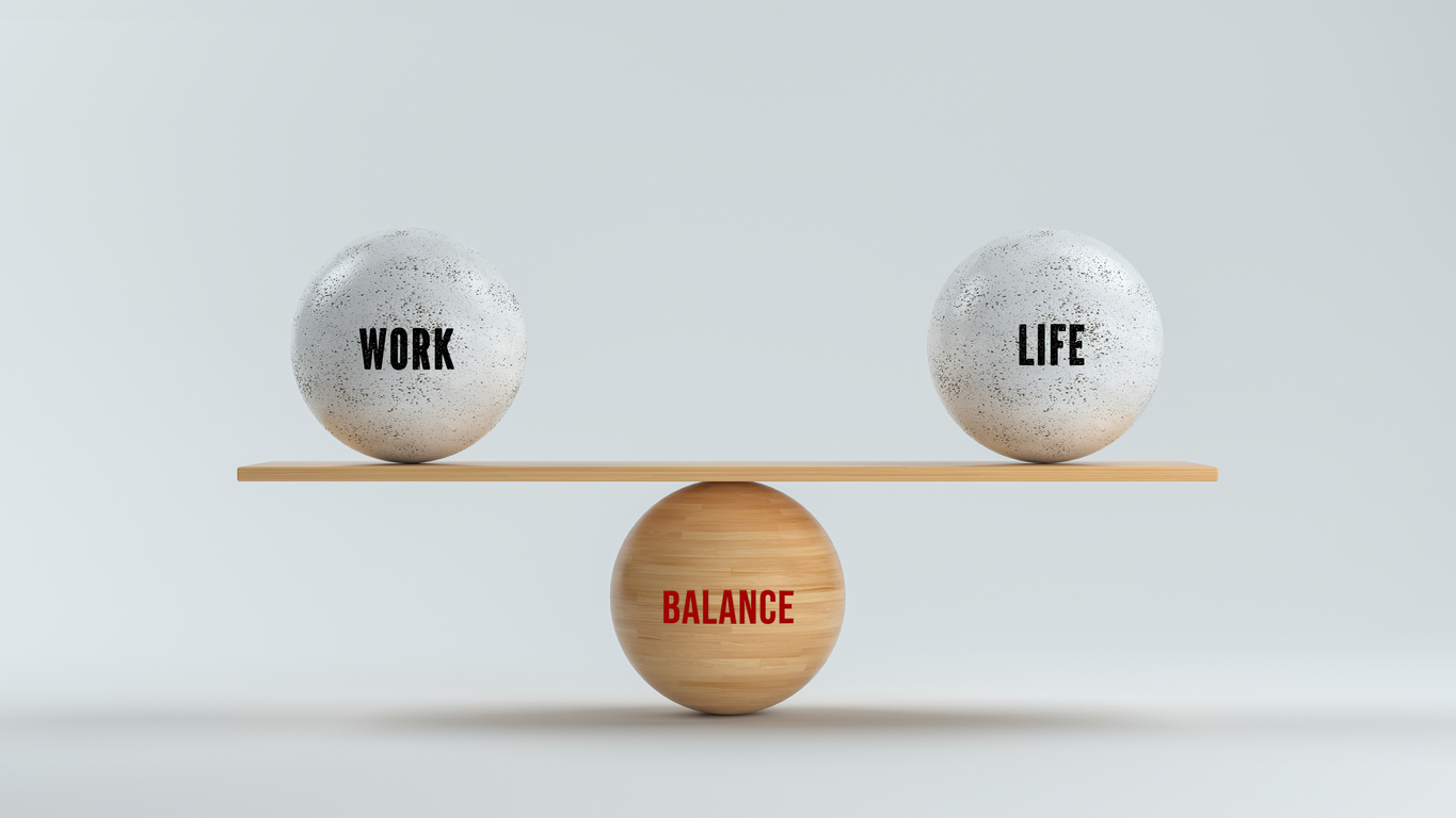 2 items on top of a wood with label work and life, that is on top of a round item where it's written "balance".