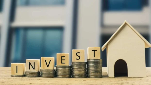 The word invest on top of coins that is increasing to the right towards a house.