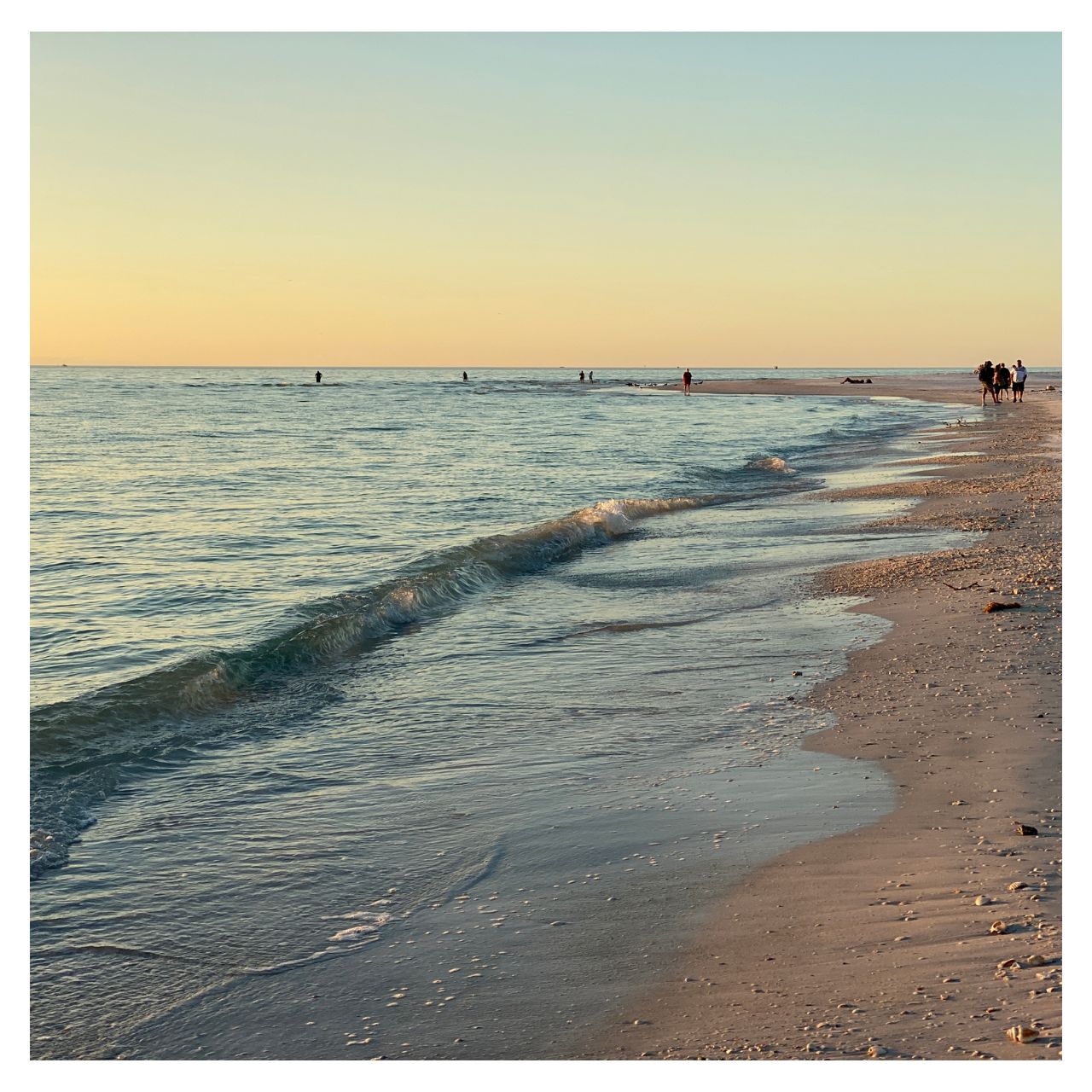 A beach with some people from afar and with great sky.
