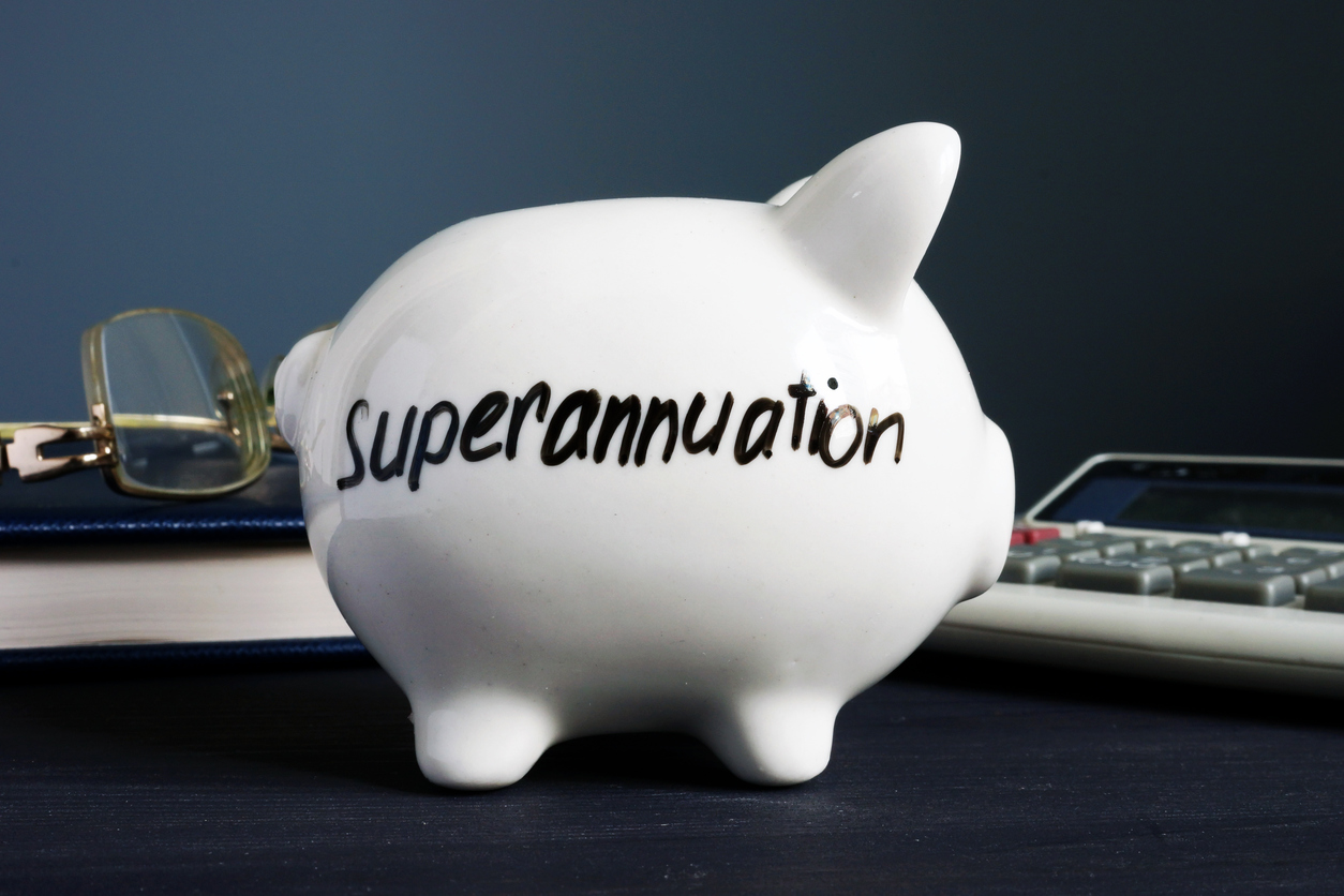 A piggy bank with 'superannuation' written on it, with eyeglass on calculator on the background.