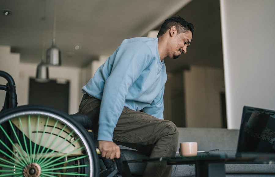 man in wheelchair moving to couch
