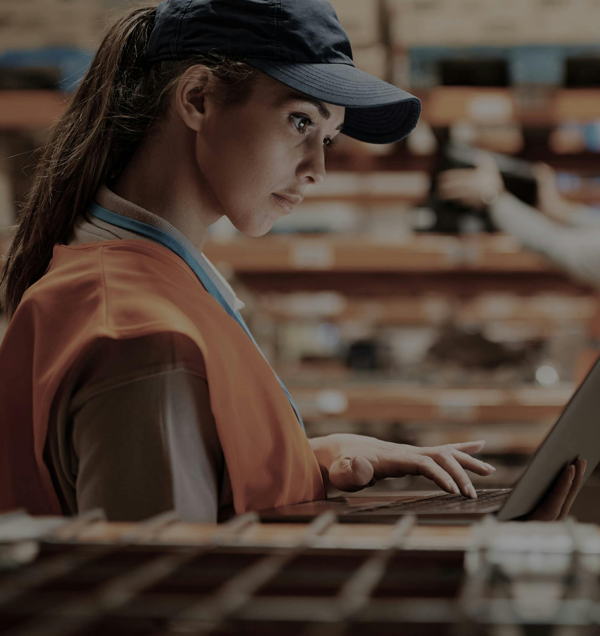 women in orange vest typing on computer