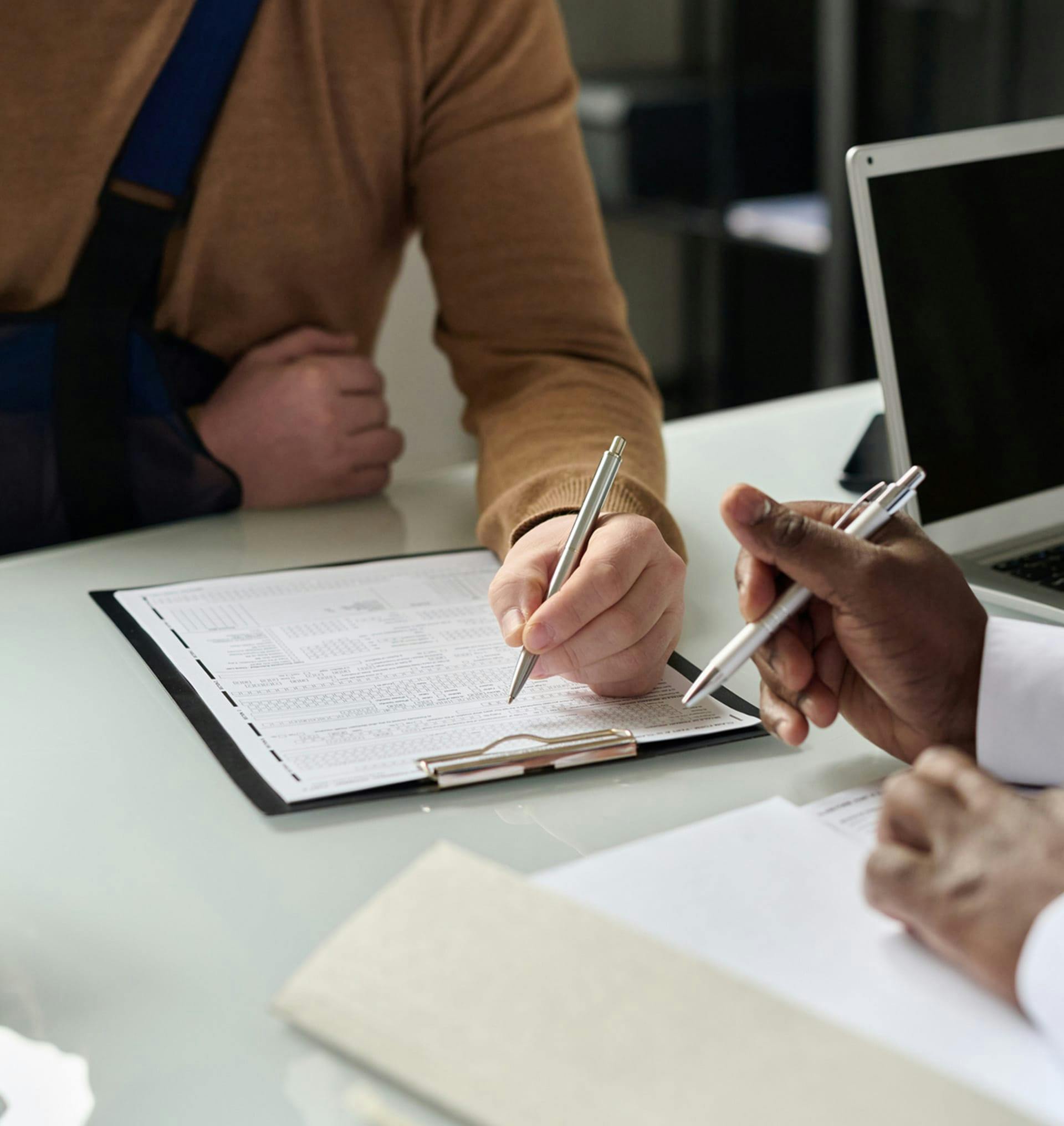 two people writing on clipboard