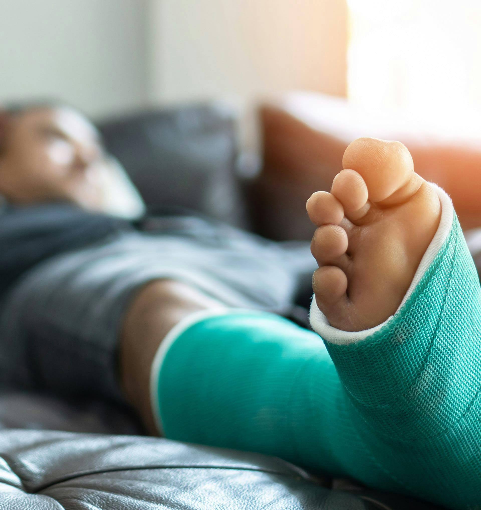 man laying on couch with a cast on his leg