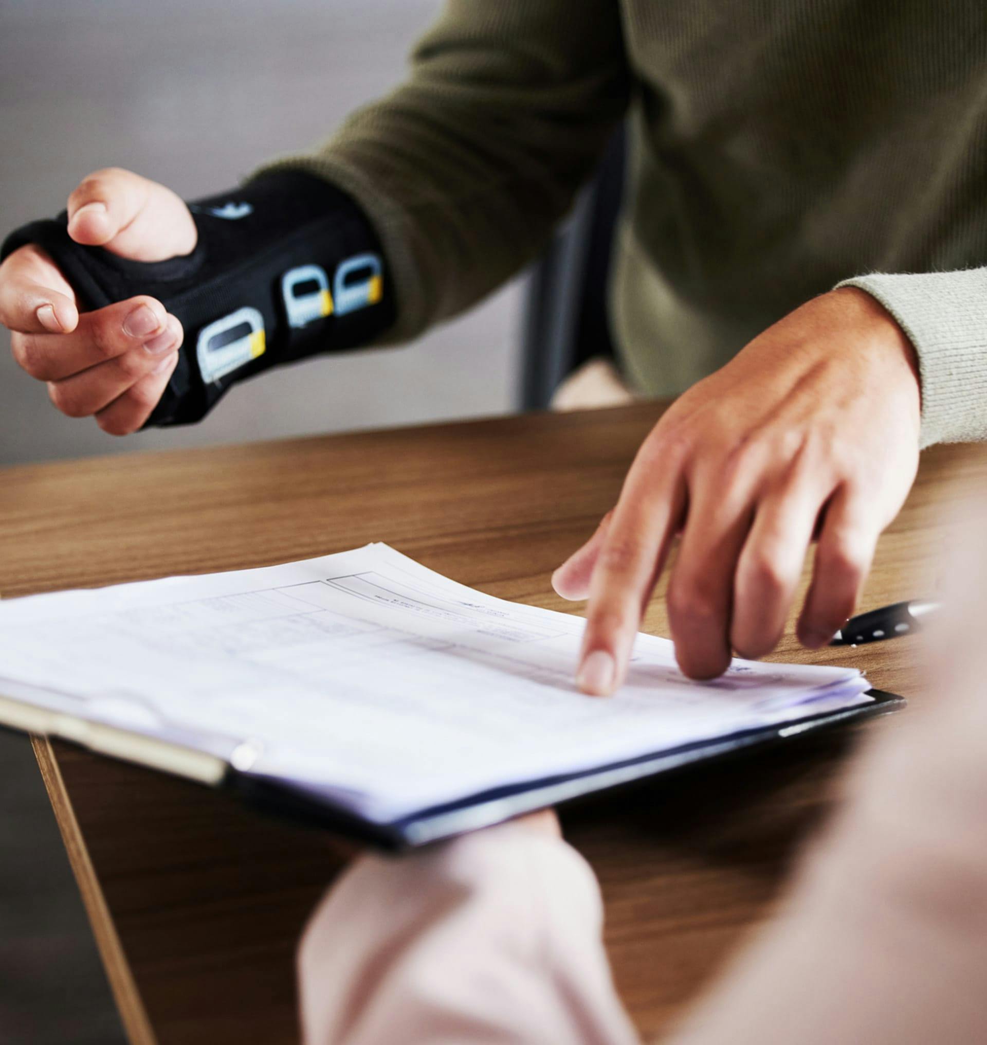 person in arm cast pointing at clipboard