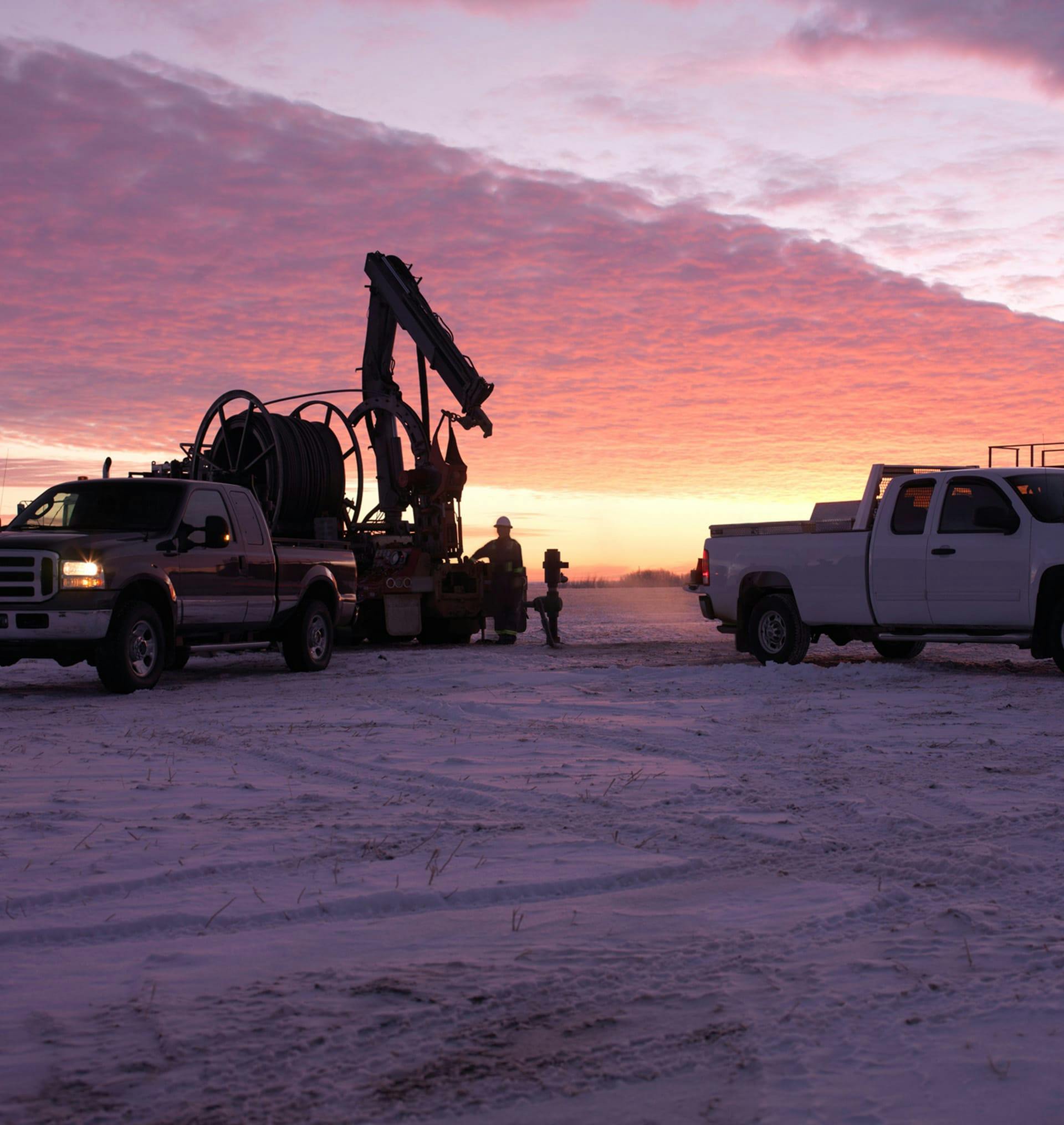 two trucks next to an oil drill